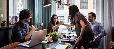 Menschen an einem Tisch mit Arbeitsutensilien klatschen sich ab