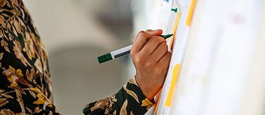 Hand schreibt auf Tafel mit Stift