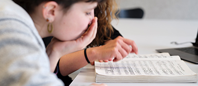 Zwei Studentinnen, die vertieft in ein Notenbuch blicken