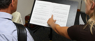Instrumentalunterricht, Lehrerin zeigt Akkordeonschüler Notenstellen