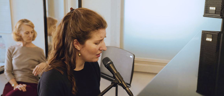 Jazz-Sängerin mit Mikrofon singt an einem Klavier