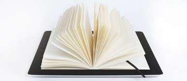 Ansicht eines Tablets worauf ein offenes Buch liegt. 