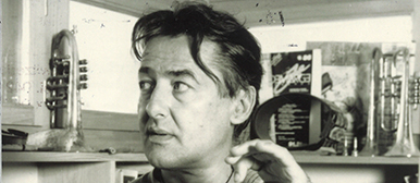 Portrait Hans Kennel inmitten vor Blasinstrumenten und Büchern