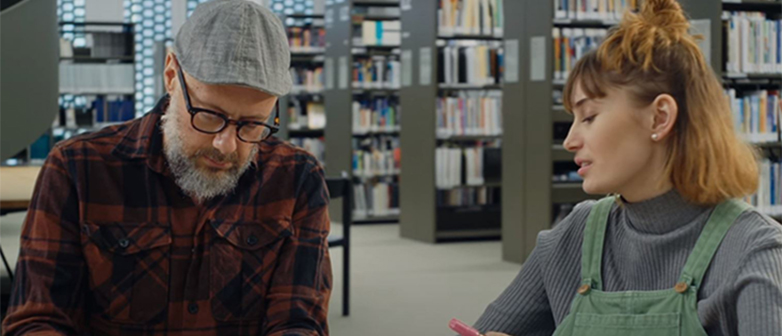 Marc Bernegger und eine Studentin sitzen in der Bibliothek und sprechen zusammen
