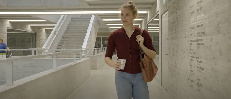 Eine junge Frau geht durch das Gebäude des Departements Musik mit einer Tasche über der Schulter