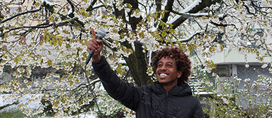 Migrant beim Aufnehmen von Tönen vor einem Baum im Aussenraum