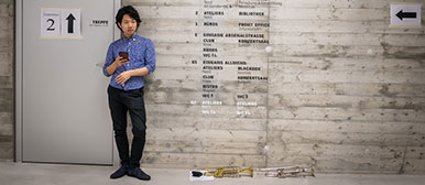 Ein asiatischer Musik-Student lehnt sich an eine Wand. 