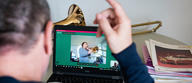 Mann dirigiert vor einem Laptop über das Internet