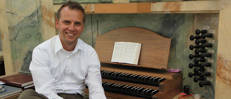 Mann neben einer Orgel