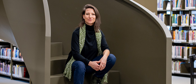 Sarah Keusch sitzt auf der Treppe in der Bibliothek