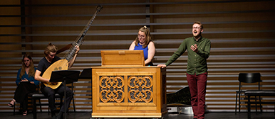 Elias Winzeler mit anderen Musiker:innen auf einer Bühne, Harmonium und Laute