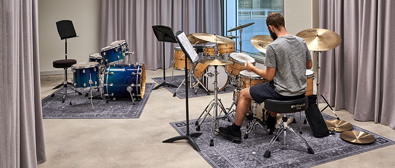 Student übt Schlagzeug in einem Unterrichtszimmer des neuen Musik-Gebäudes. 
