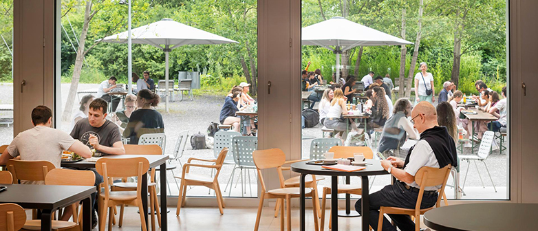 Blick aus dem Bistro auf den Aussenbereich, Menschen sitzen an Tischen