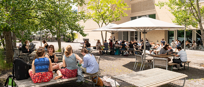 Blick aus dem Bistro auf den Aussenbereich, Menschen sitzen an Tischen