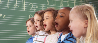 fünf Kinder die zusammen singen vor einer grünen Wandtafel
