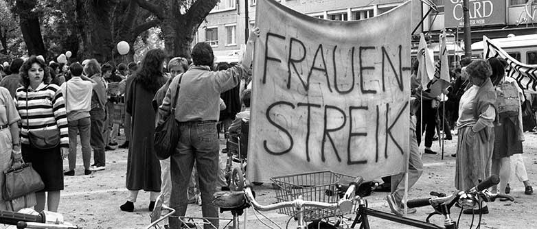 Eine Gruppe Personen halten eine Fahne mit der Aufschrift 