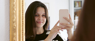 Mädchen mit dem Handy vor dem Spiegel