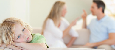 Blondes Kind im Vordergrund und Streitende Eltern im Hintergrund