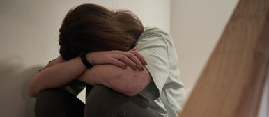 Frau sitzt auf Treppe und verdeckt ihr Gesicht