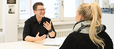 Zwei Frauen führen ein Gespräch und sitzen am Tisch