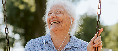 Das neue «Alter», Seniorin hört auf einer Schaukel mit Kopfhörern Musik