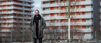 Ein Mann steht vor zwei Wohnsiedlungen die orange Storen haben