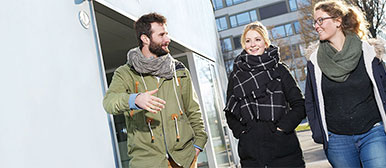 Drei Studierende, seitlich fotografiert und lächelnd