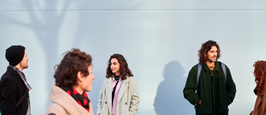 Männer und Frauen vor einer blauen Wand am Departement Soziale Arbeit