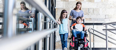 Frau mit Mädchen und Bub im Rollstuhl
