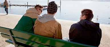 Jugendliche sitzen am See auf einer Bank