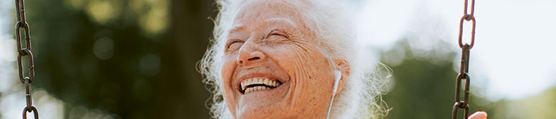 Das neue «Alter», Seniorin hört auf einer Schaukel mit Kopfhörern Musik