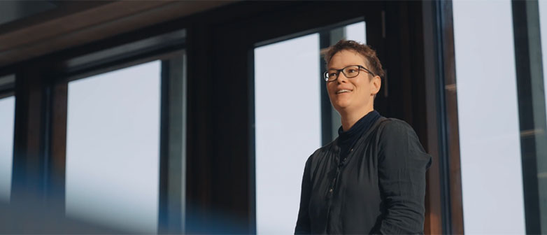 Mirjam Aschwanden, Studiengangsleiterin Bachelor of Science in Pflege der Hochschule Luzern, steht vor grossen Fenstern und spricht lächelnd in einem Unterrichtsraum.