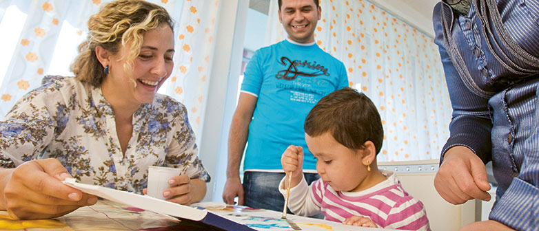 Frau begleitet ein Kleinkind beim Malen