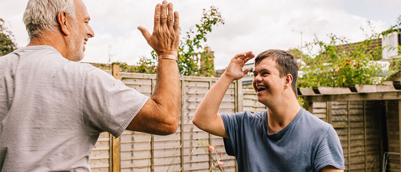 Father And His Son With Down Syndrome Playing In The Garden