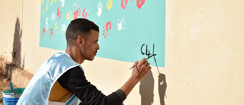 Mann malt an einer Wand