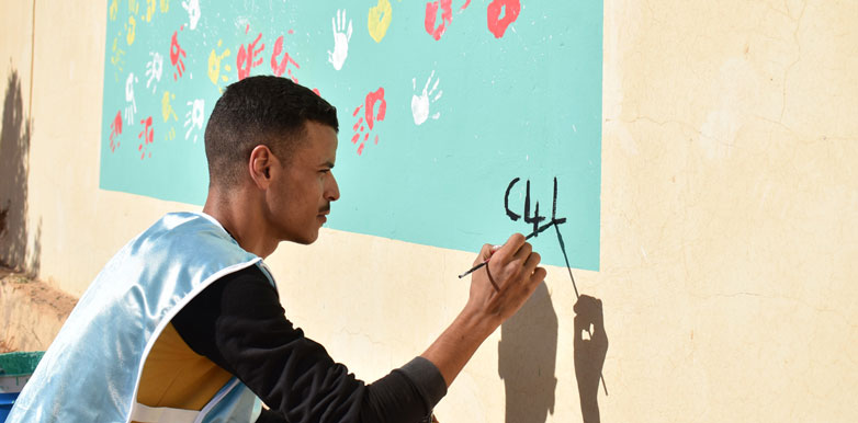 Mann in Afrika bemalt Wand mit Kinderzeichnungen