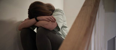 Frau sitzt auf Treppe mit gesenktem Kopf