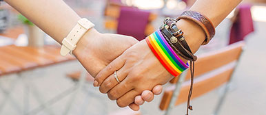 Zwei Frauenhände mit Regenbogen-Armband