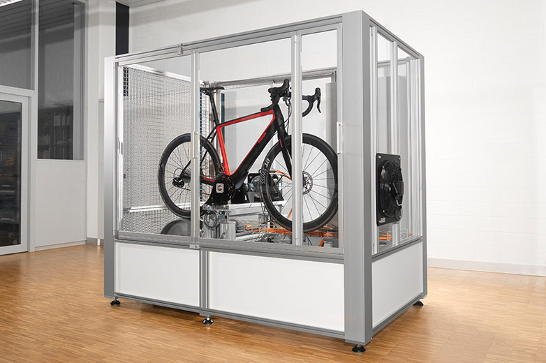 Ein Fahrrad befindet sich auf einem Prüfstand in einem leeren Raum.