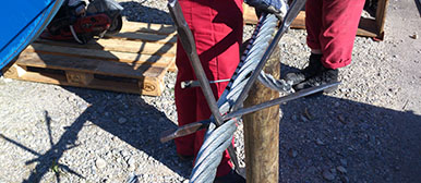 Symbolbild Seilmechanik: zwei Personen in Arbeitskleidung arbeiten an einem Drahtseil