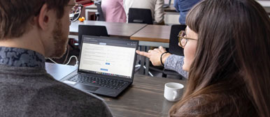 Zwei Forschende betrachten Informationen am Laptop