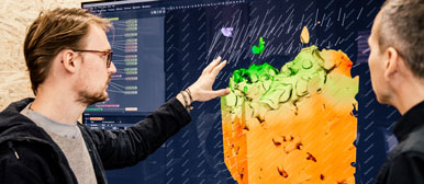 Zwei Forschende betrachten eine Visualisierung auf einem grossen Bildschirm.