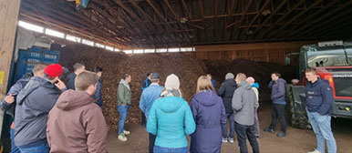 Gruppe hört sich einen Vortrag in einem Holzlager an