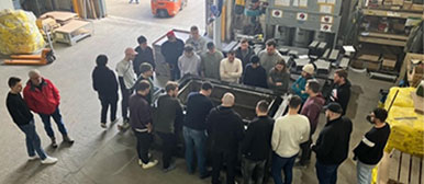 Gruppe von Studierenden und Dozierenden um einen Ofen versammelt