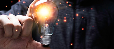 Foto zeigt einen Mann, der eine leuchtende Glühbirne in der Hand hält.