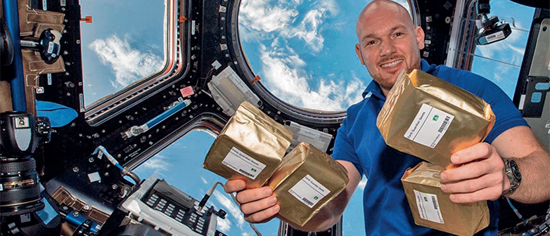 Alexander Gerst auf der Iss, hält Samenpakete hoch