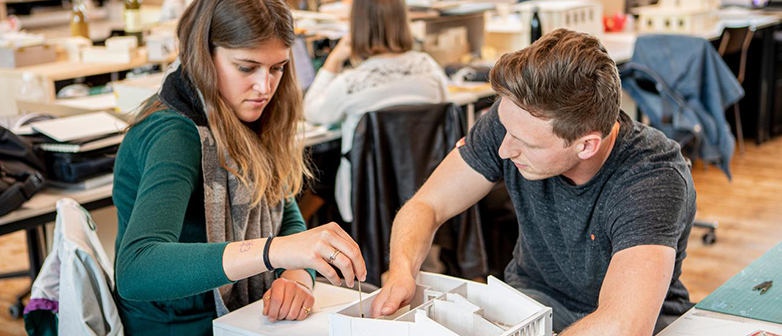 Two students at the model of a house