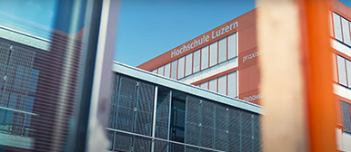 Ein graues und ein rotes Gebäude des Departements Technik und Architektur aus einem Fenster fotografiert