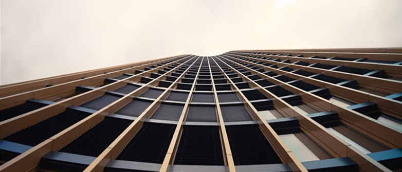 Modernes Gebäude mit Fenstern, die kupferfarben umrahmt sind, aus der Froschperspektive in den Himmel fotografiert