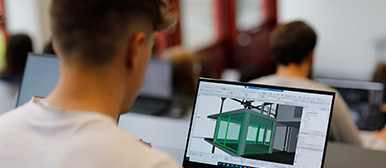 Ein Student betrachtet in seinem Laptop eine 3D-Gebäudekonstruktion